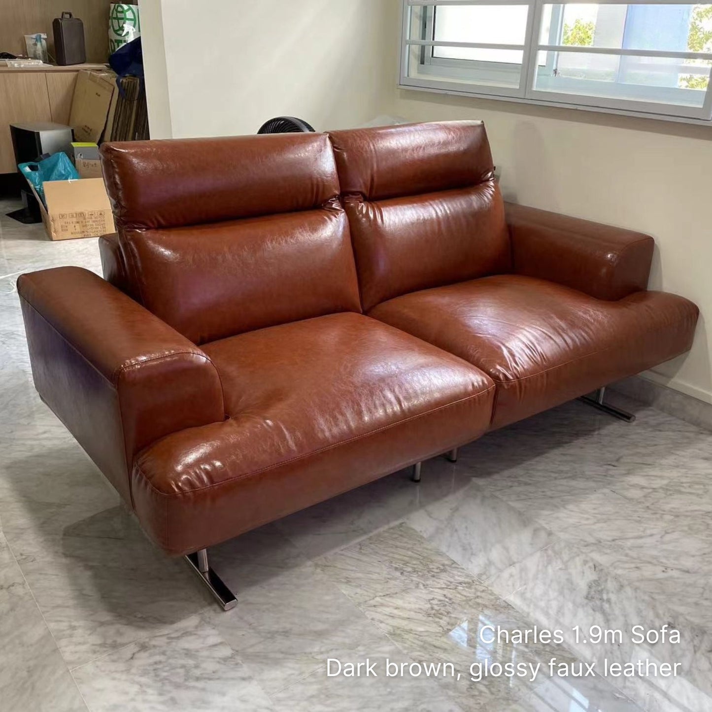 Brown leather sofa in a room with a window and boxes.