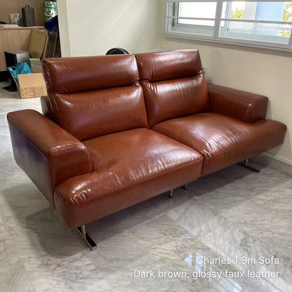 Brown leather sofa in a room with a window and boxes.