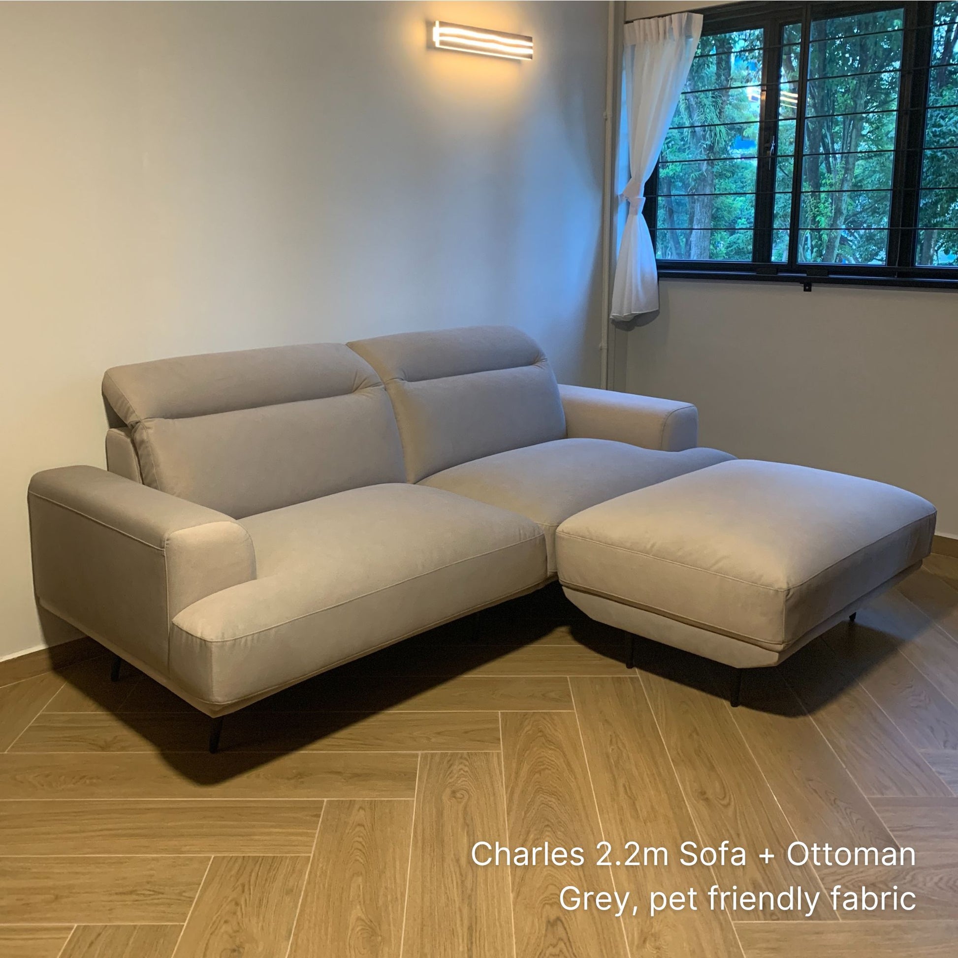 Gray pet frienld fabric Charles 3 setaer 220cm sofa with matching ottoman in a room with a window and wooden floor.
