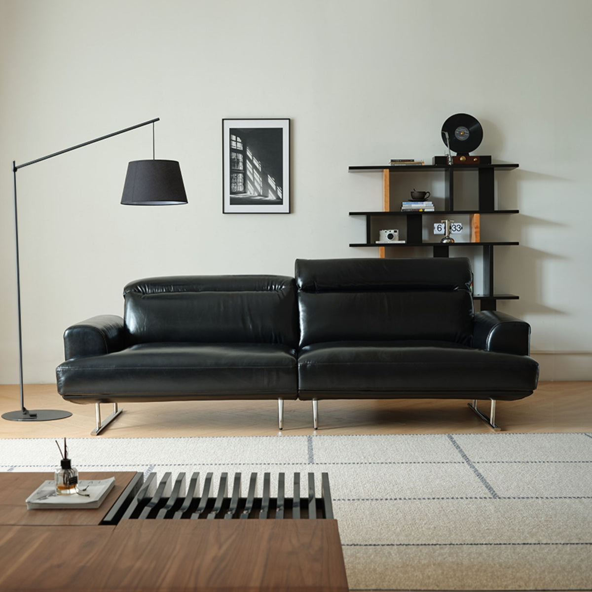 Modern living room with a black leather sofa, floor lamp, and bookshelf.