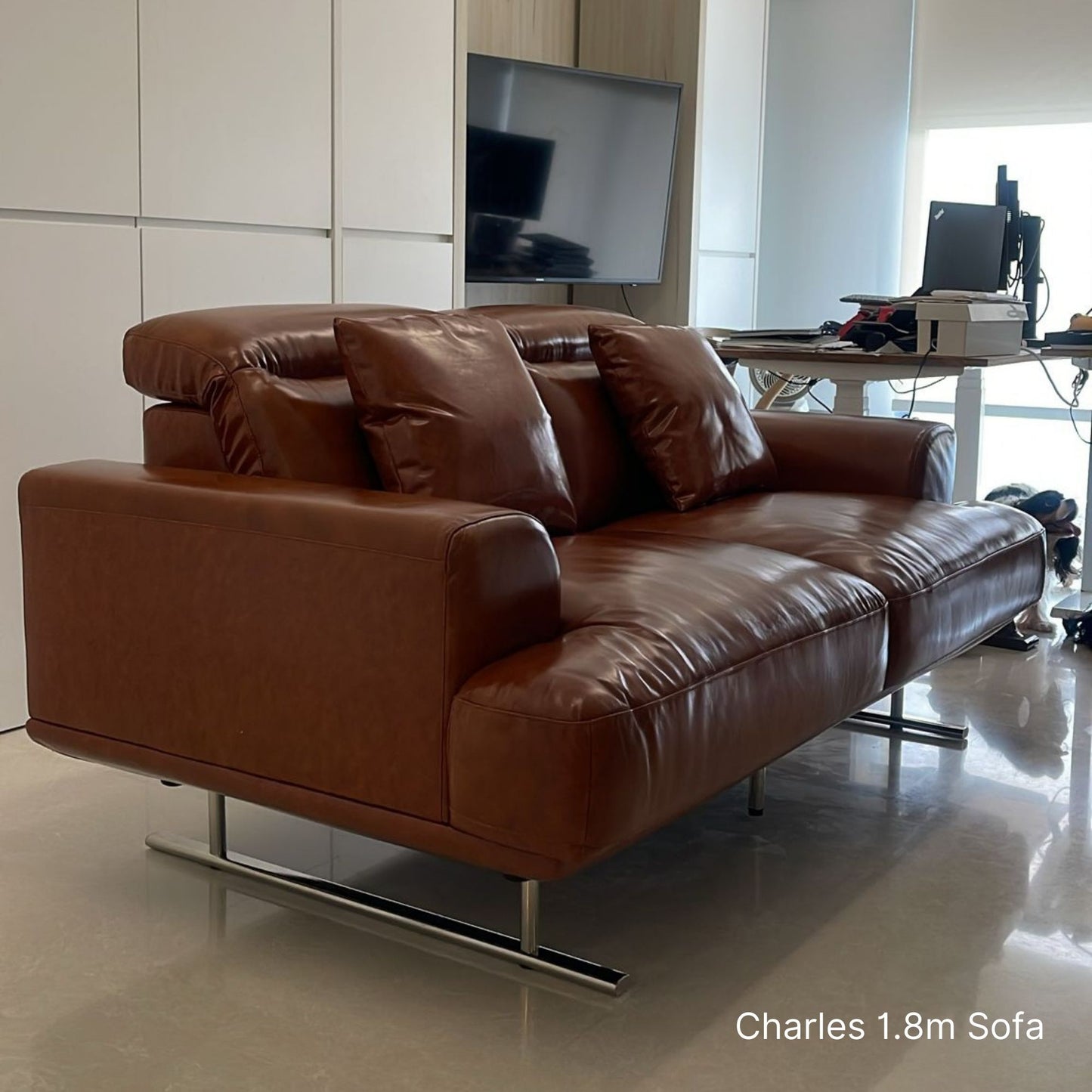 Brown 2 seater Charles half leather sofa in a modern living room setting with a TV and desk.