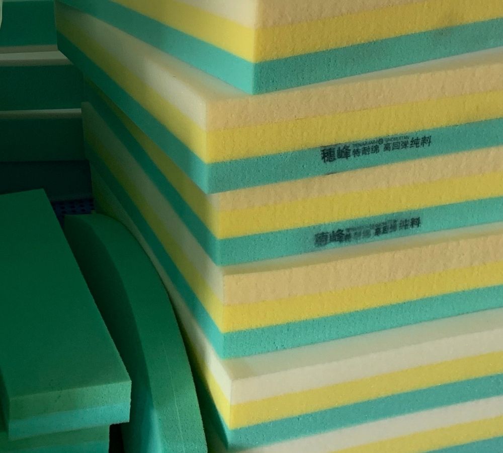 Stacked layers of green, yellow, and white foam padding with Chinese characters printed on the side.