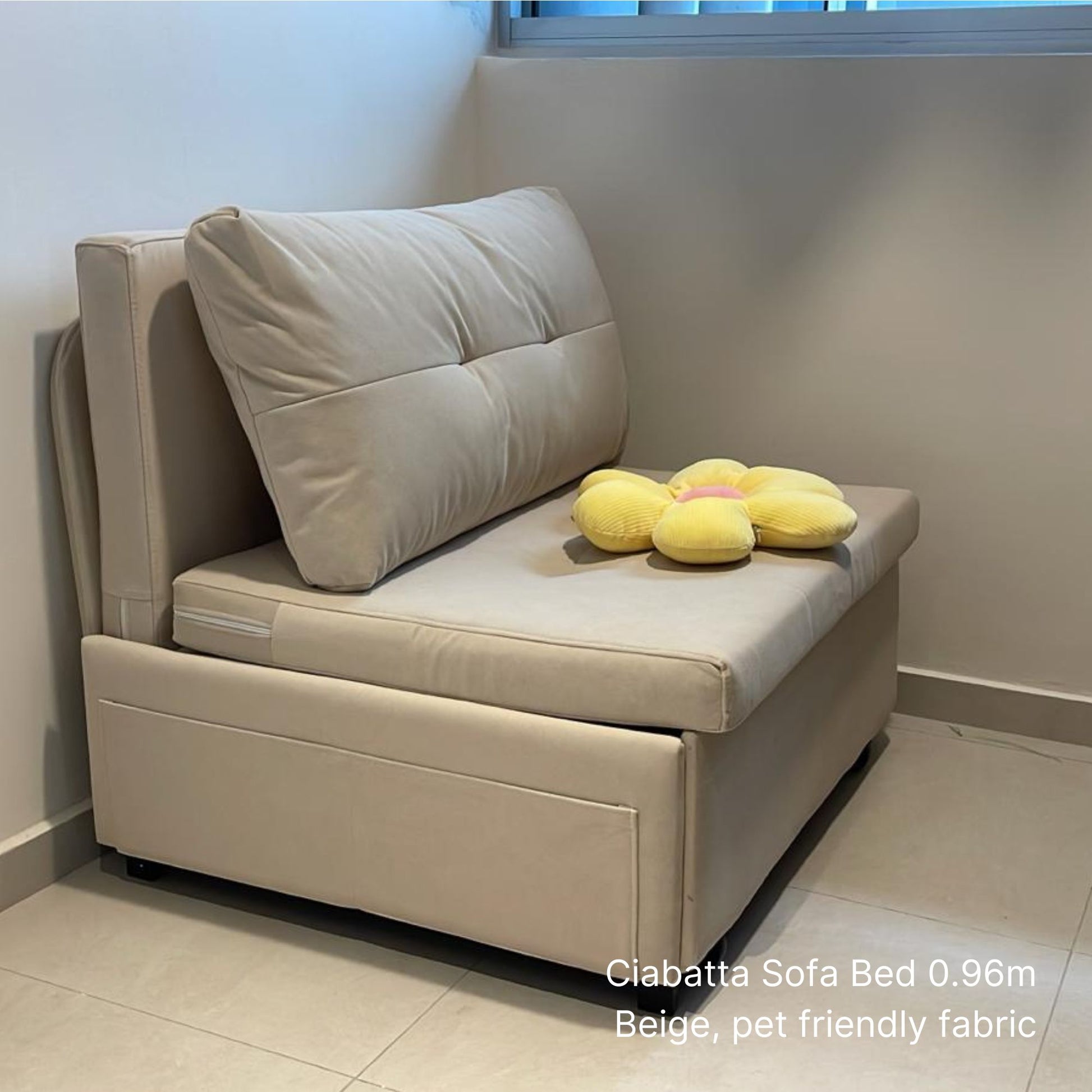 Beige sofa bed with a pillow and plush toys in a room.
