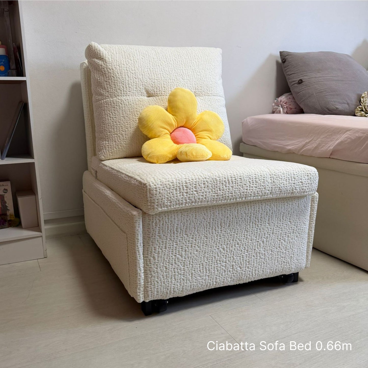White sofa bed with a yellow flower-shaped pillow in a bedroom setting.