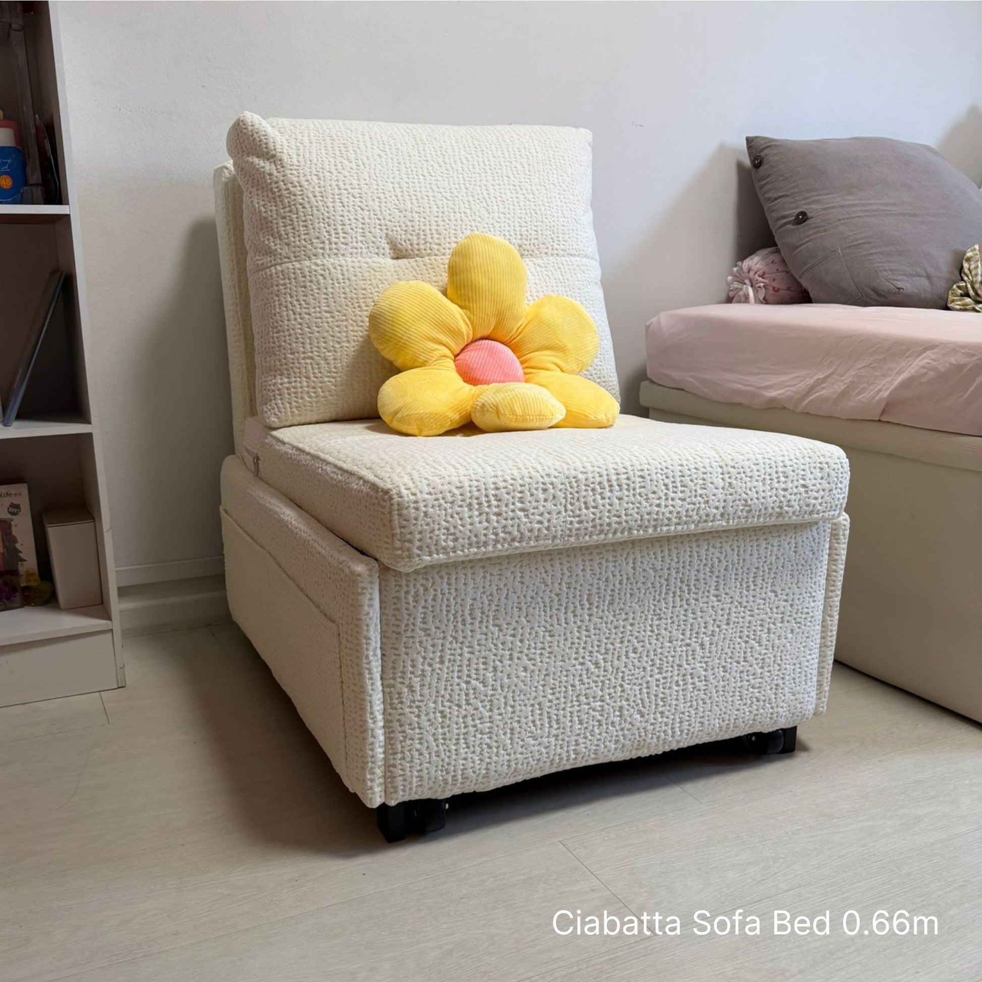 White sofa bed with a yellow flower-shaped pillow in a bedroom setting.