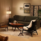 Cozy living room with a dark green sofa, wooden coffee table, and armchair with a fur throw.