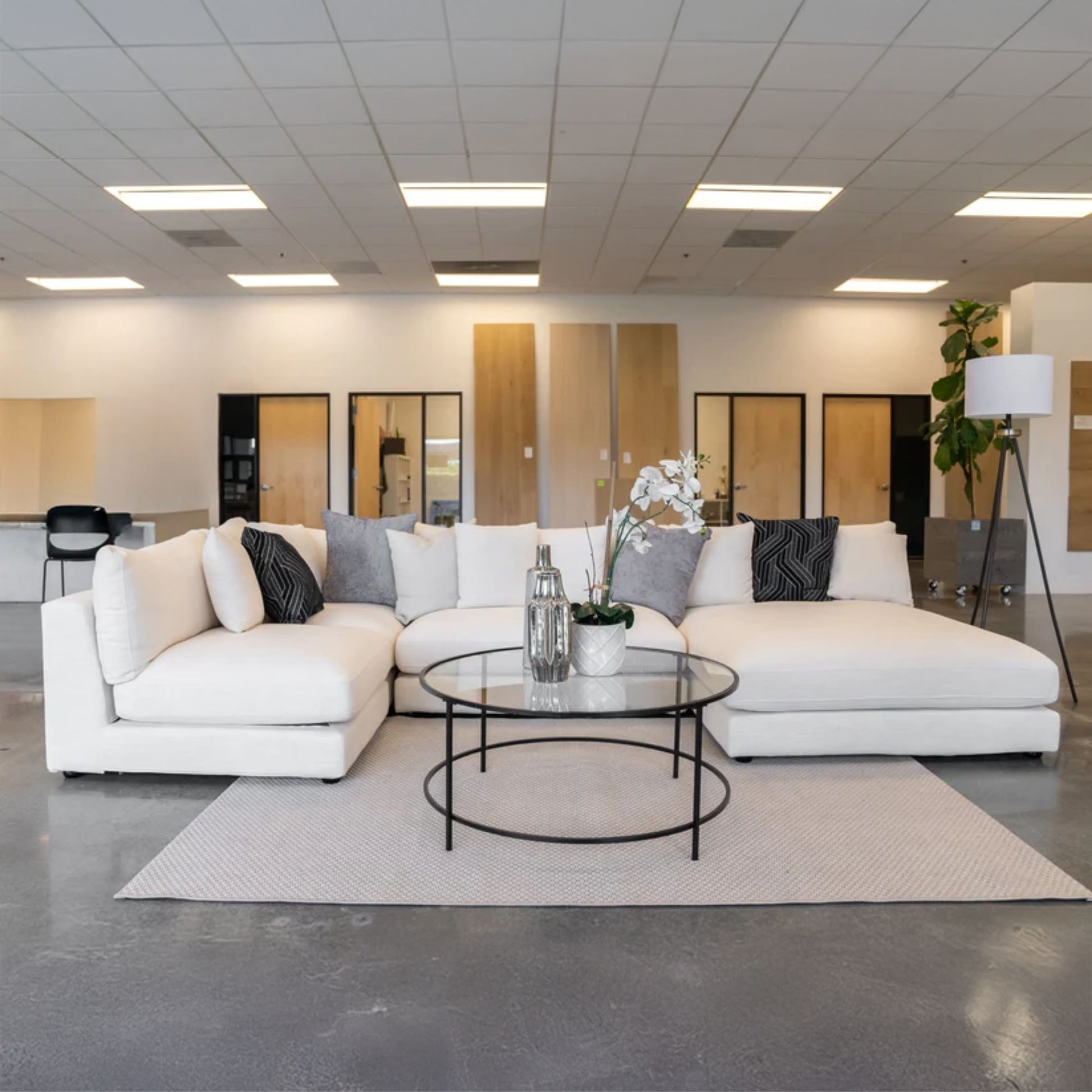 White Claudia U shaped sectional sofa with right chaise with decorative pillows in a showroom setting