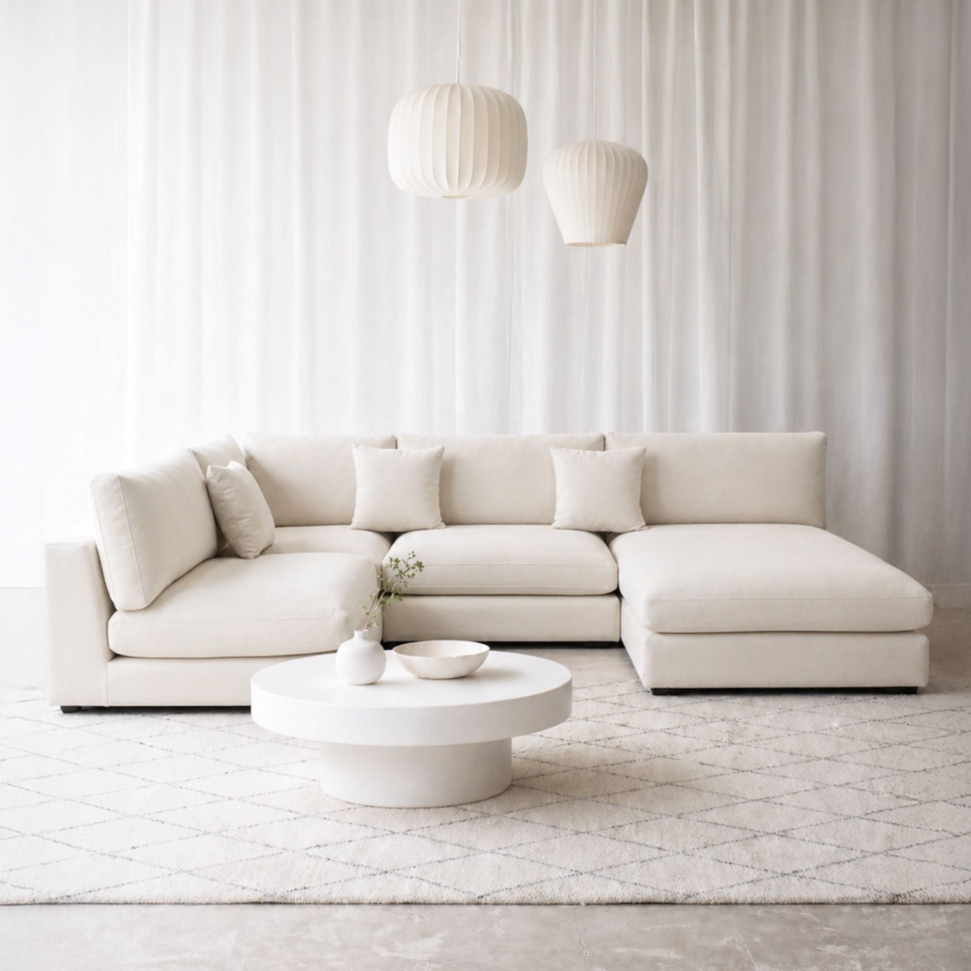 White Claudia U shaped sectional sofa with right chaise with decorative pillows in a showroom setting