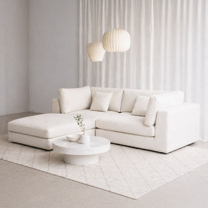 Modern white sectional sofa in a minimalistic living room with white walls and floor.