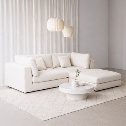 Modern living room with a white sectional sofa and round coffee table.