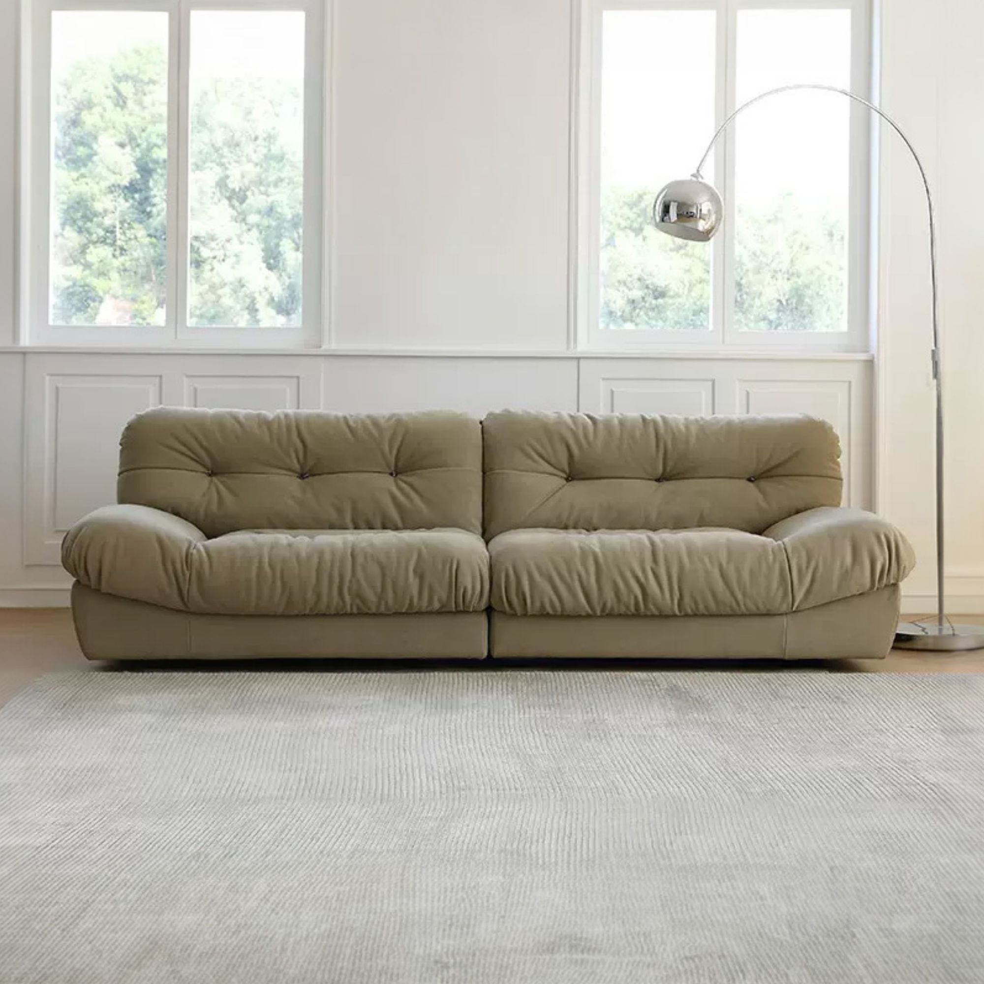 Green sofa in a room with large windows and a lamp.