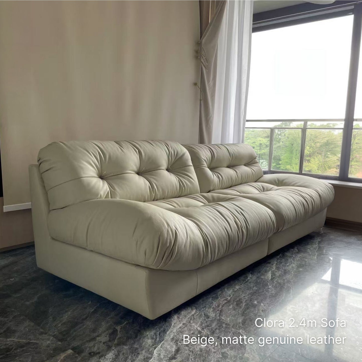 3 seater 240cm beige top grain leather Clora half leather sofa in a room with large windows and curtains.