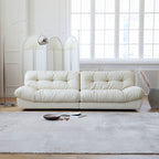 White sofa in a modern living room with large windows and minimal decor.