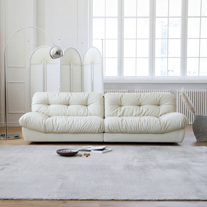 White sofa in a modern living room with large windows and minimal decor.