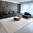 A modern living room featuring a black tufted sectional sofa, a matching black chaise lounge, a round coffee table, and a large light beige textured area rug on a gray tiled floor.