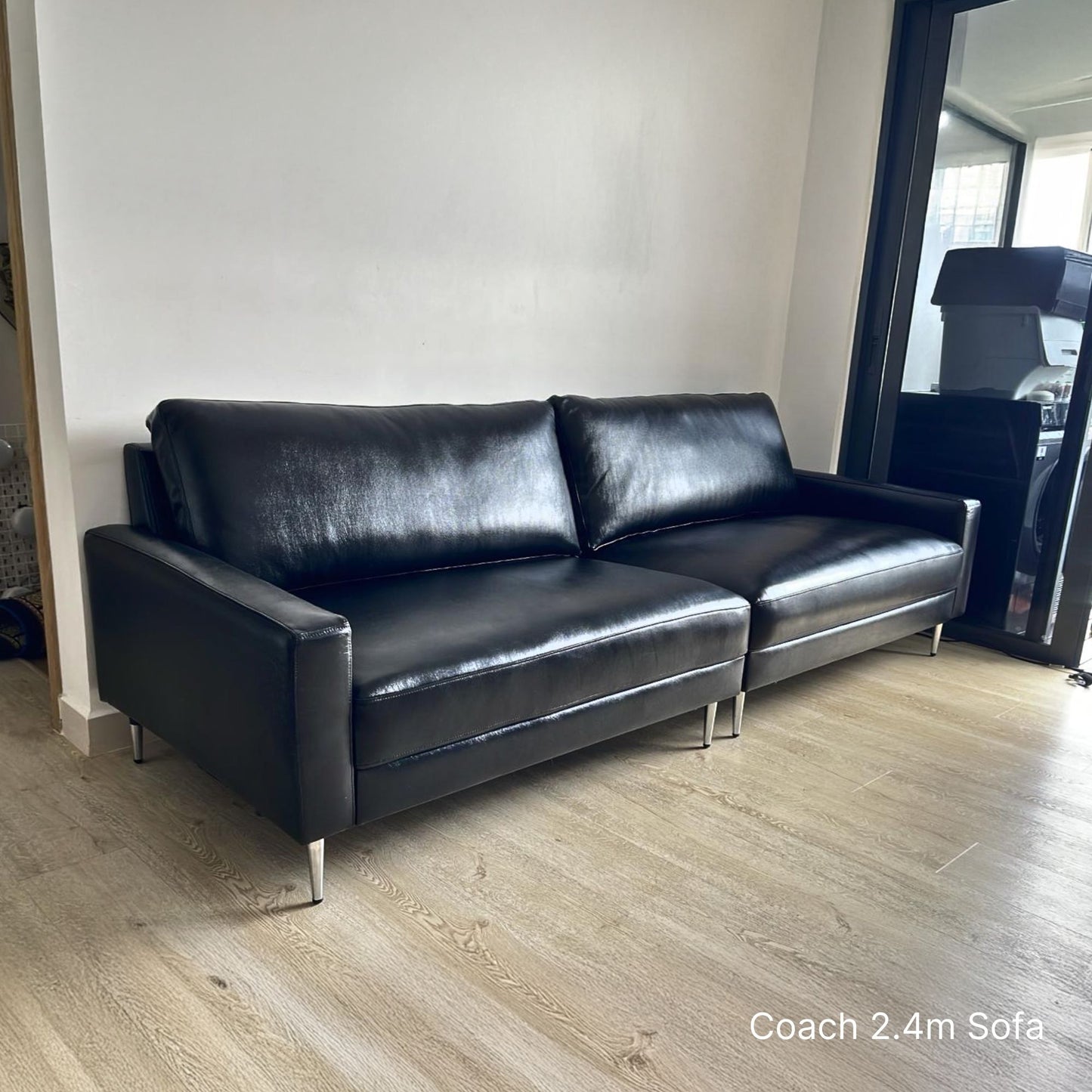 Delivered 240cm 3 seater black leather Coach sofa in a room with wooden flooring