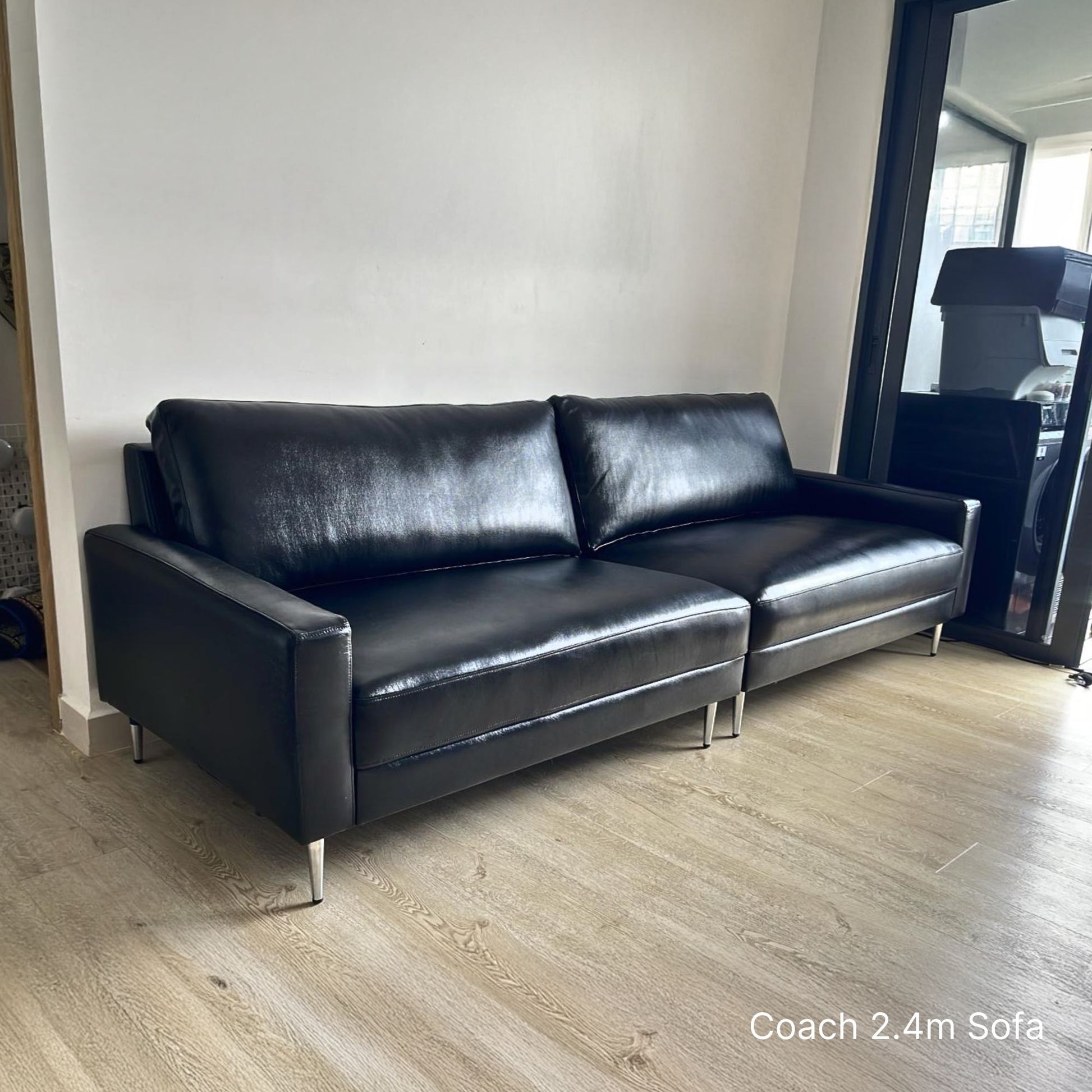 Delivered 3 seater 240cm Coach black leather sofa sample in a room with wooden flooring.
