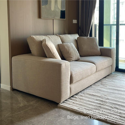 3 seater 200cm beige Coastal fabric sofa in a modern living room with abstract art and large windows.