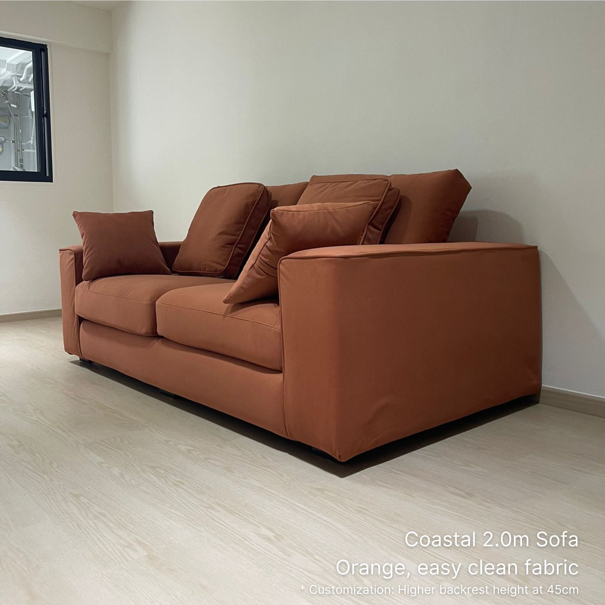 Orange 3 seater Coastal fabric sofa in a minimalistic room with light wood flooring and white walls.