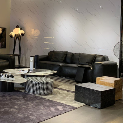 Modern living room with black leather sofa, marble coffee table, and decorative elements.
