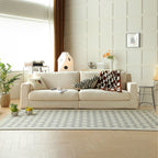 Modern living room with a off white sofa, decorative pillows, and a patterned rug.
