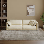 White sofa in a living room with a abstract painting on the wall and a plant.