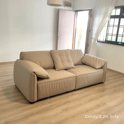 3 seater beige Comfy half leather sofa in a room with wooden flooring and a window.
