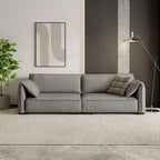 Gray sofa in a modern living room with a plant and abstract art on the wall.