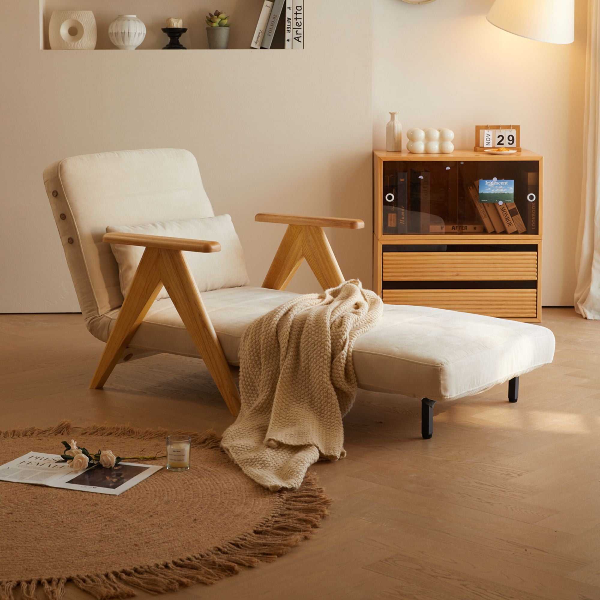 Beige armchair with a blanket in a room with wooden floor and shelves.