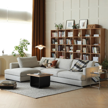 Modern living room with a sectional sofa, bookshelf, and decorative items.