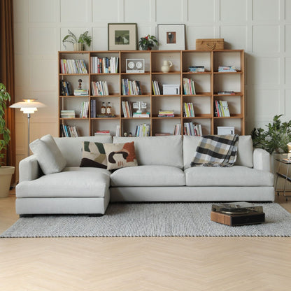 Living room with a sectional sofa, bookshelf, and decorative items.