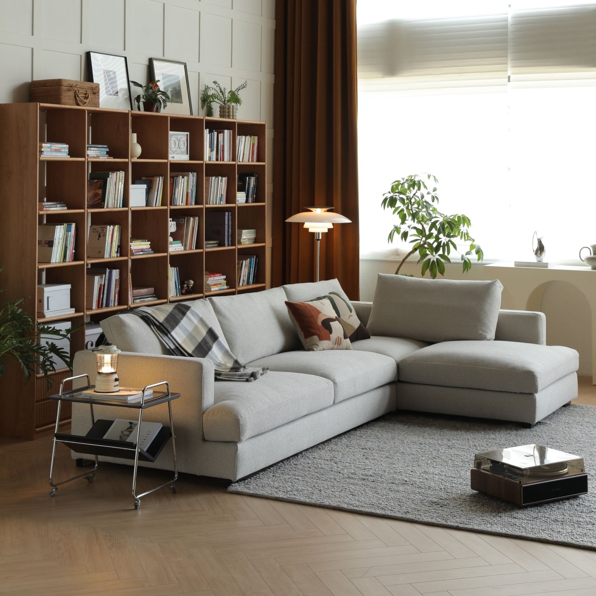 Modern living room with a sectional sofa, bookshelf, and decorative items.