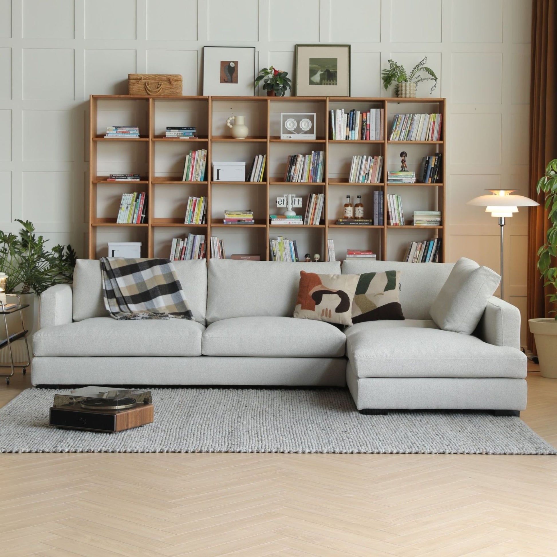 Gray sectional sofa in a living room with a bookshelf and decor items.