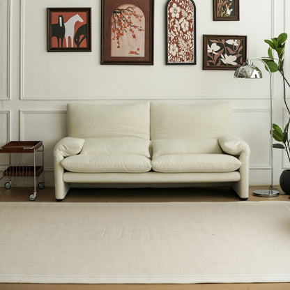 Beige sofa in a room with decorative wall art and a plant.