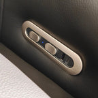Close-up of a brushed metal control panel with two round buttons and a USB-C port, mounted on a dark textured leather surface.