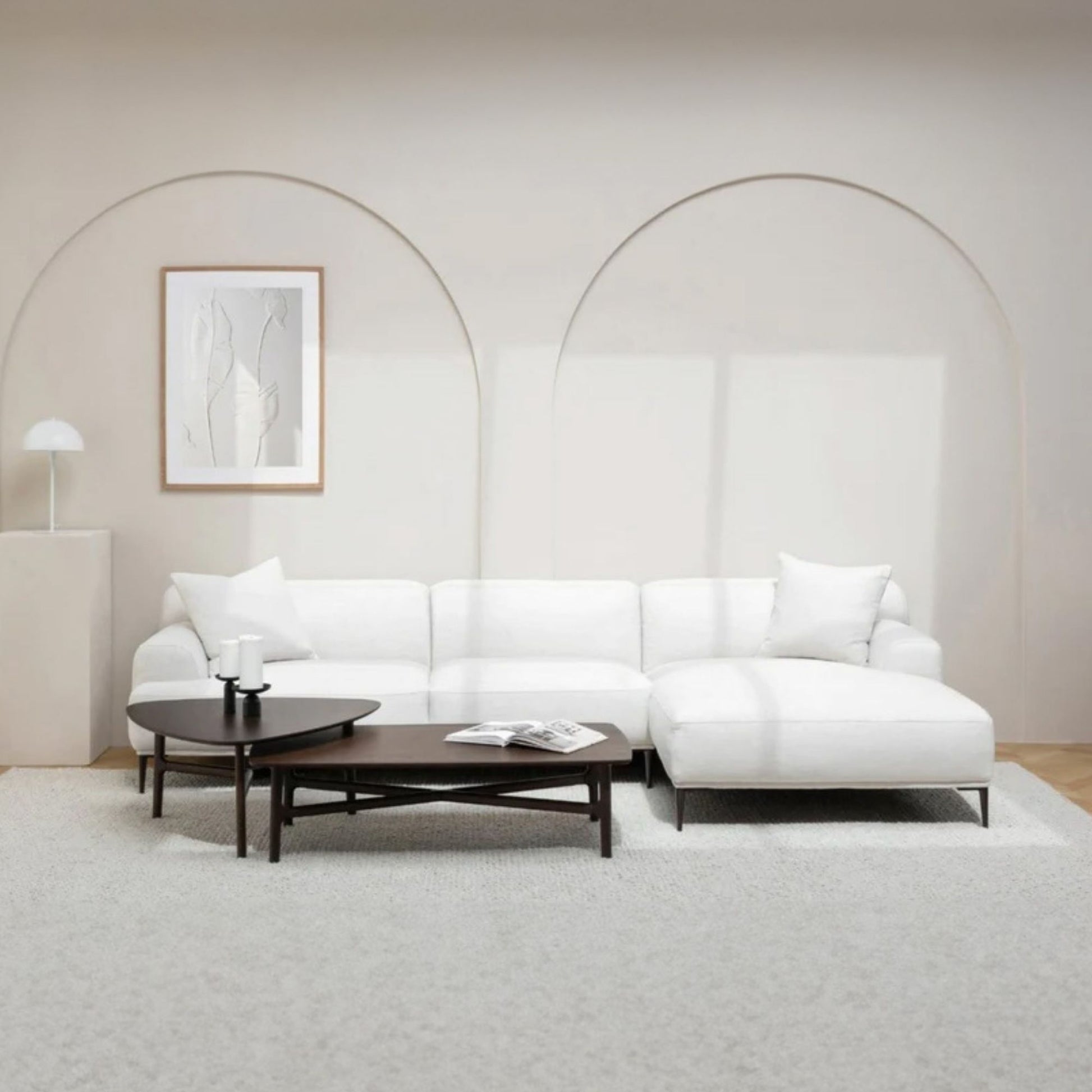 Modern white l-shaped sectional sofa in a minimalistic living room with a coffee table and decorative items.