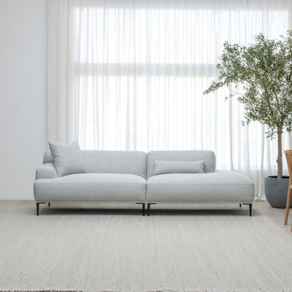 Gray sofa in a modern living room with large windows and a plant.