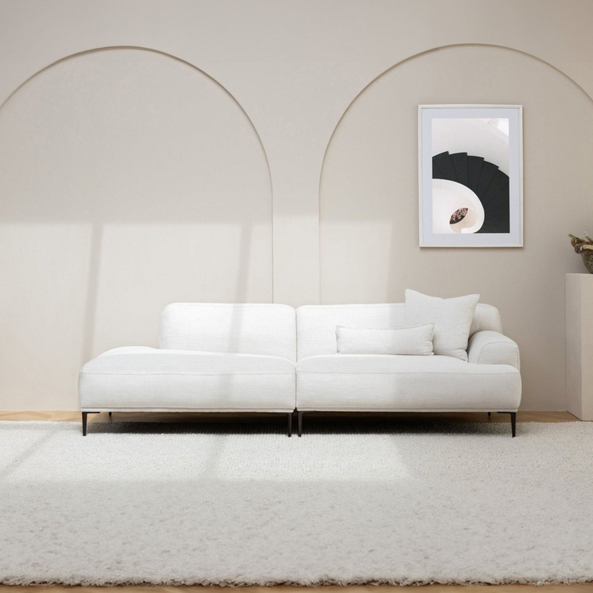 White sofa in a minimalistic room with a framed picture on the wall.