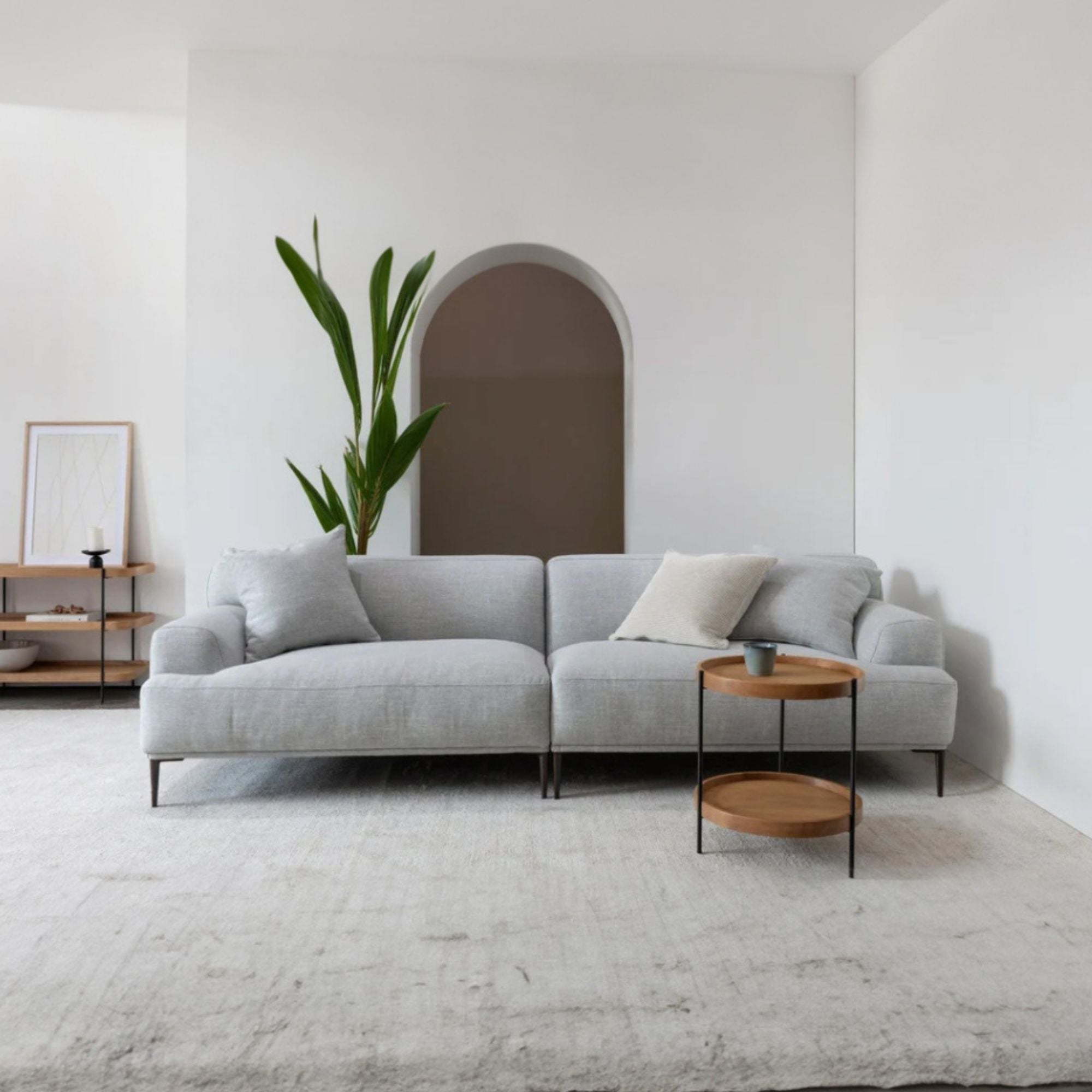 Gray sectional sofa in a modern living room with a plant and side table.