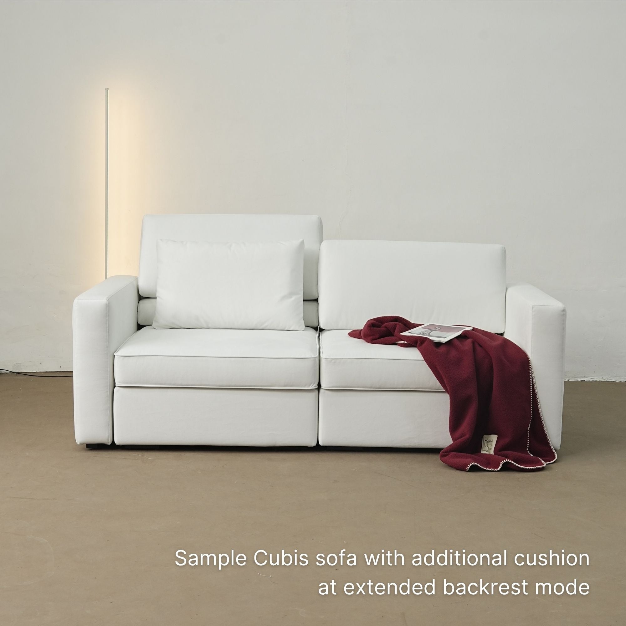 White sofa with additional cushion and red blanket in a minimalistic room.
