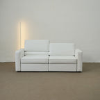 White sofa against a plain wall with a light source on the left.
