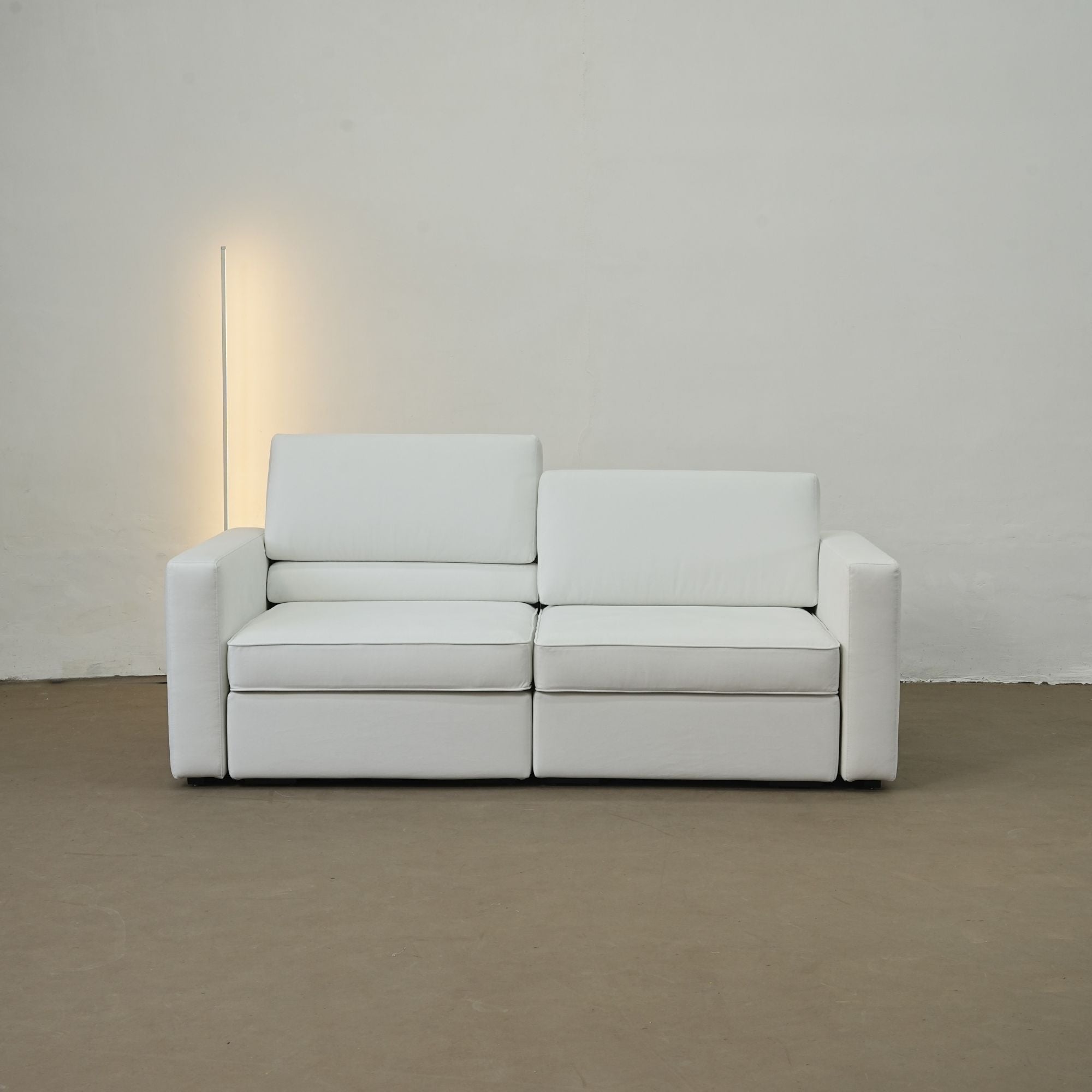 White sofa against a plain wall with a light source on the left.