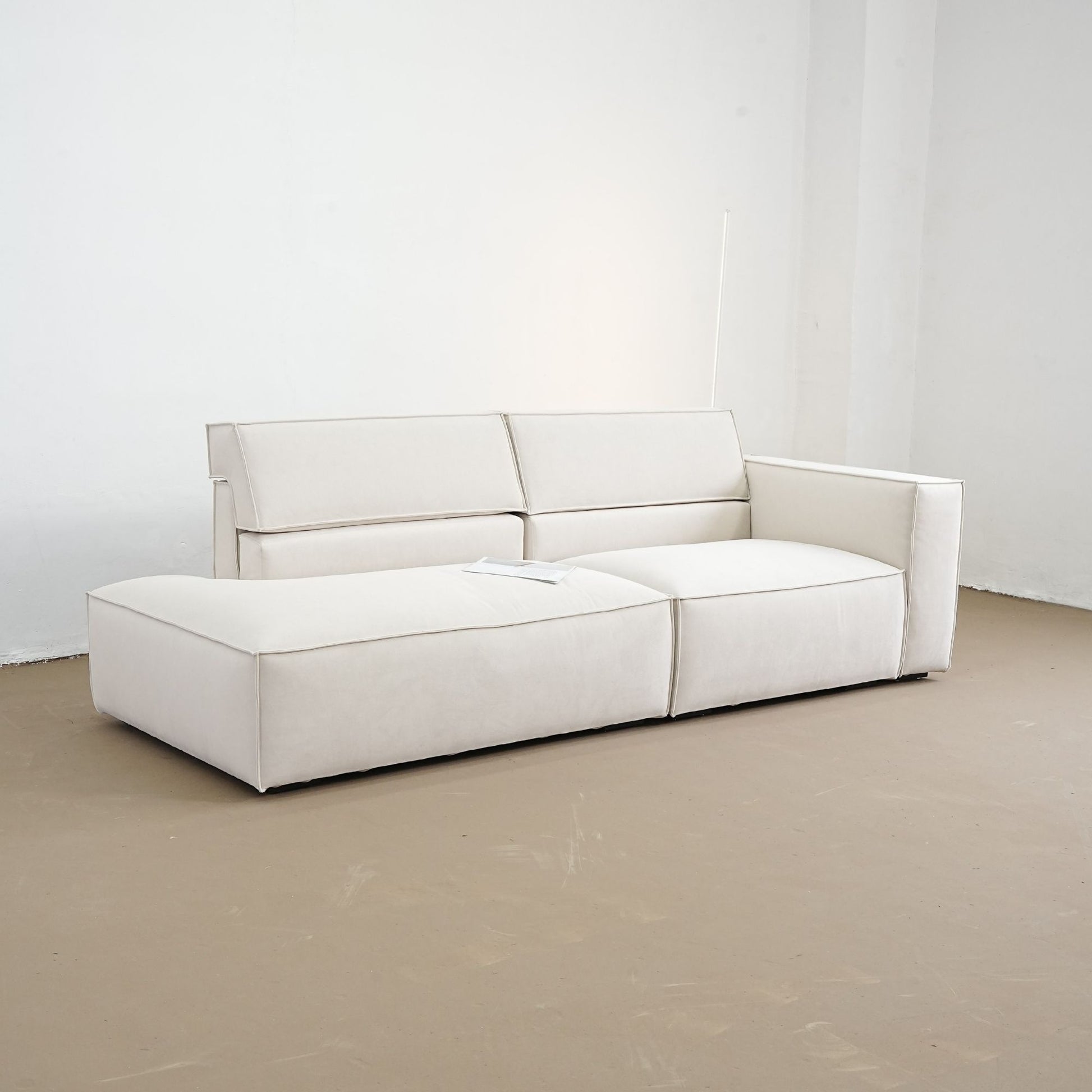 White sofa in a minimalistic room with white walls and a beige floor.