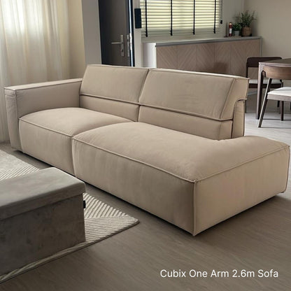 Beige sectional sofa in a living room setting with a dining area in the background.