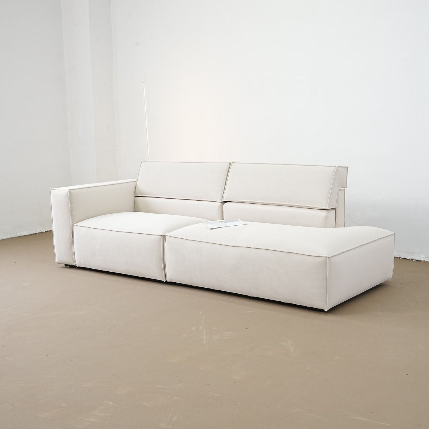 White sofa on a beige floor with a white wall background