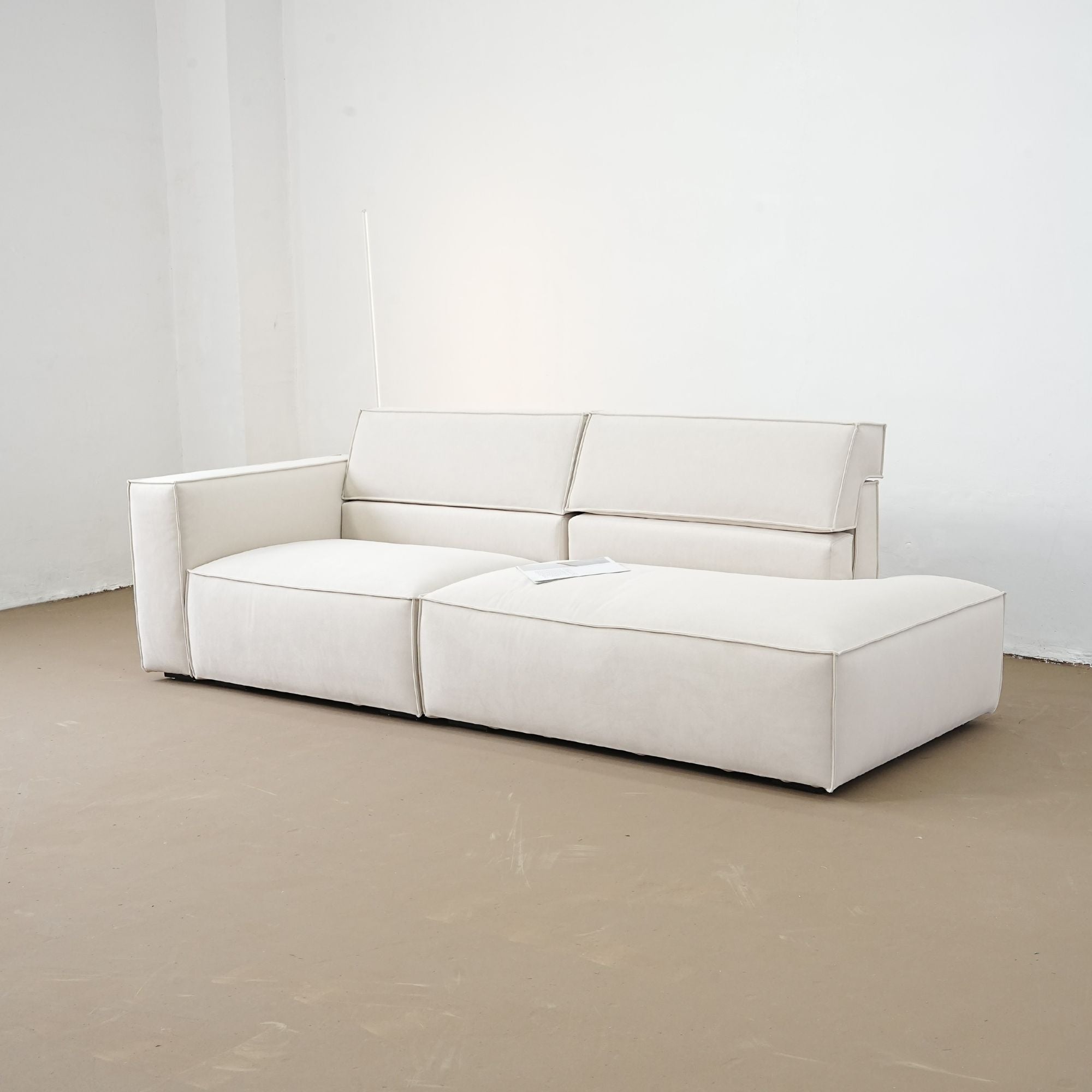 White sofa on a beige floor with a white wall background