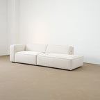 White sofa in a minimalistic room with white walls and a beige floor.