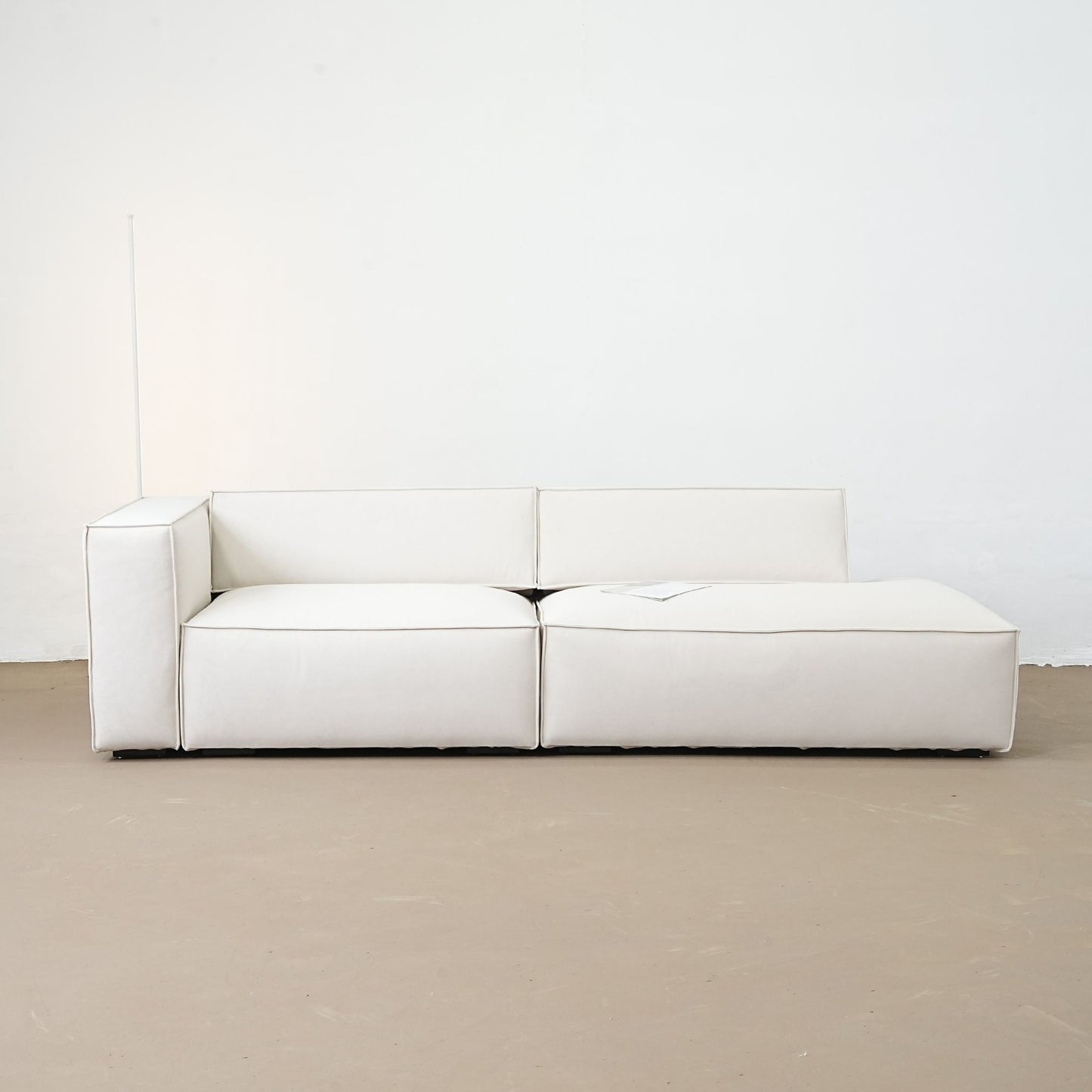 White sofa on a beige floor with a white wall background