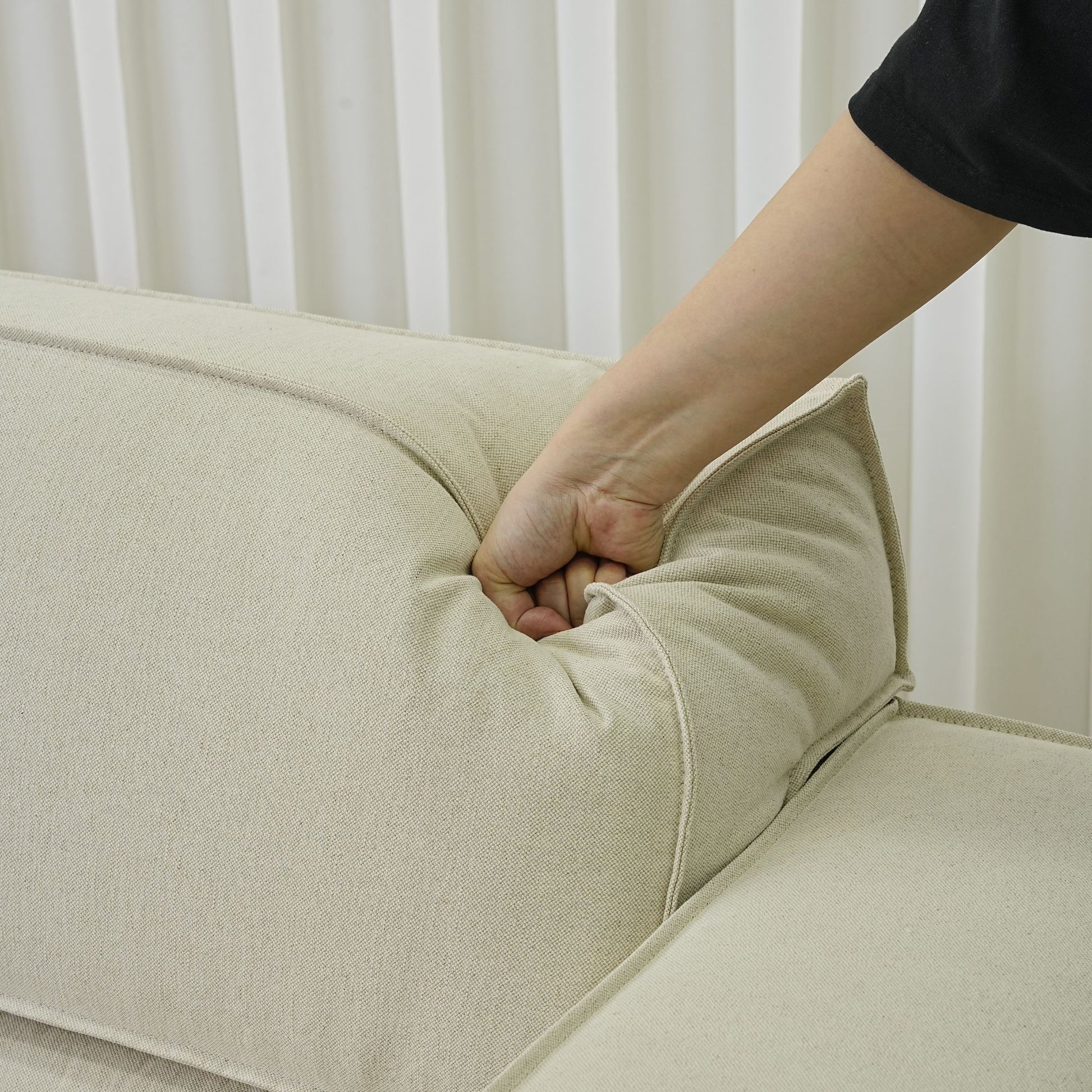 Close up view of hand pressing down on adjustable backrest portion for Cubix fabric adjustable backrest sofa