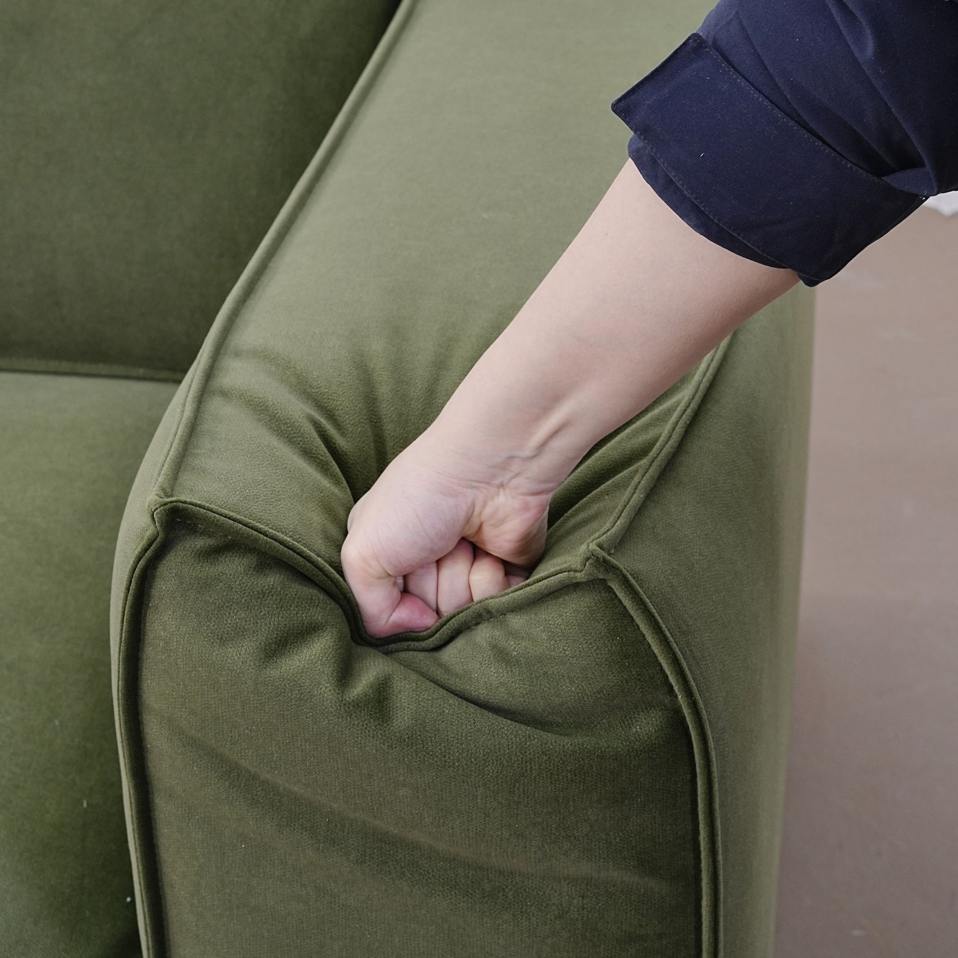 Hand pressing down on the handrest portion of Cubix fabric adjustable backrest sofa in green pet friendly fabric with a velvety feel.